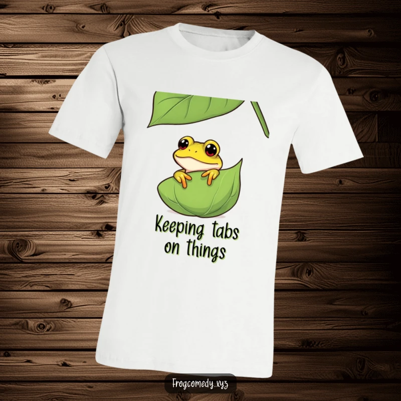 Funny curious frog t-shirt showing an amphibian peeking playfully from behind a large leaf, perfect for those who love nature and a good giggle.